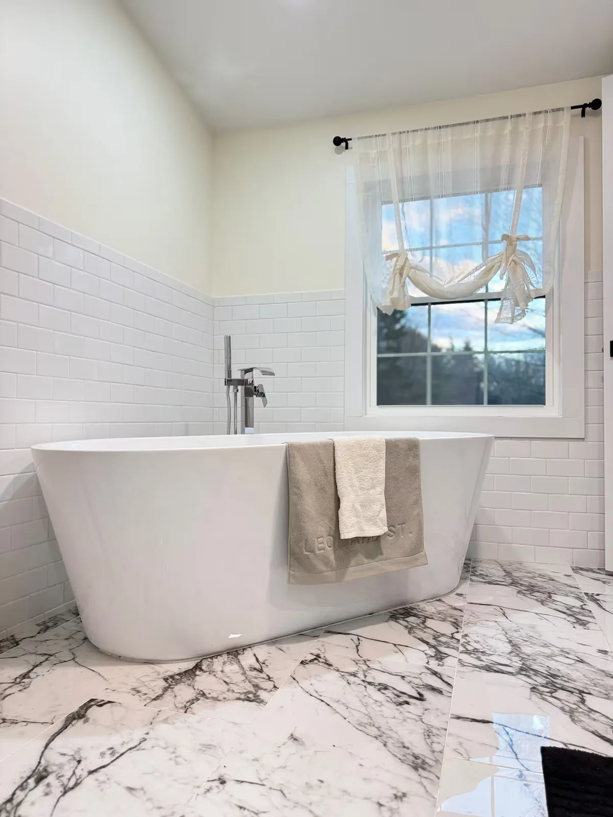 Freestanding soaking tub beside the window in the primary bath