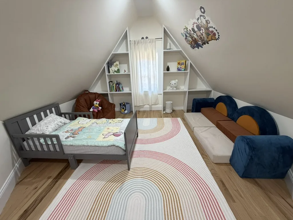 Children's room with a toddler bed, soft play couch, and an A-frame bookshelf