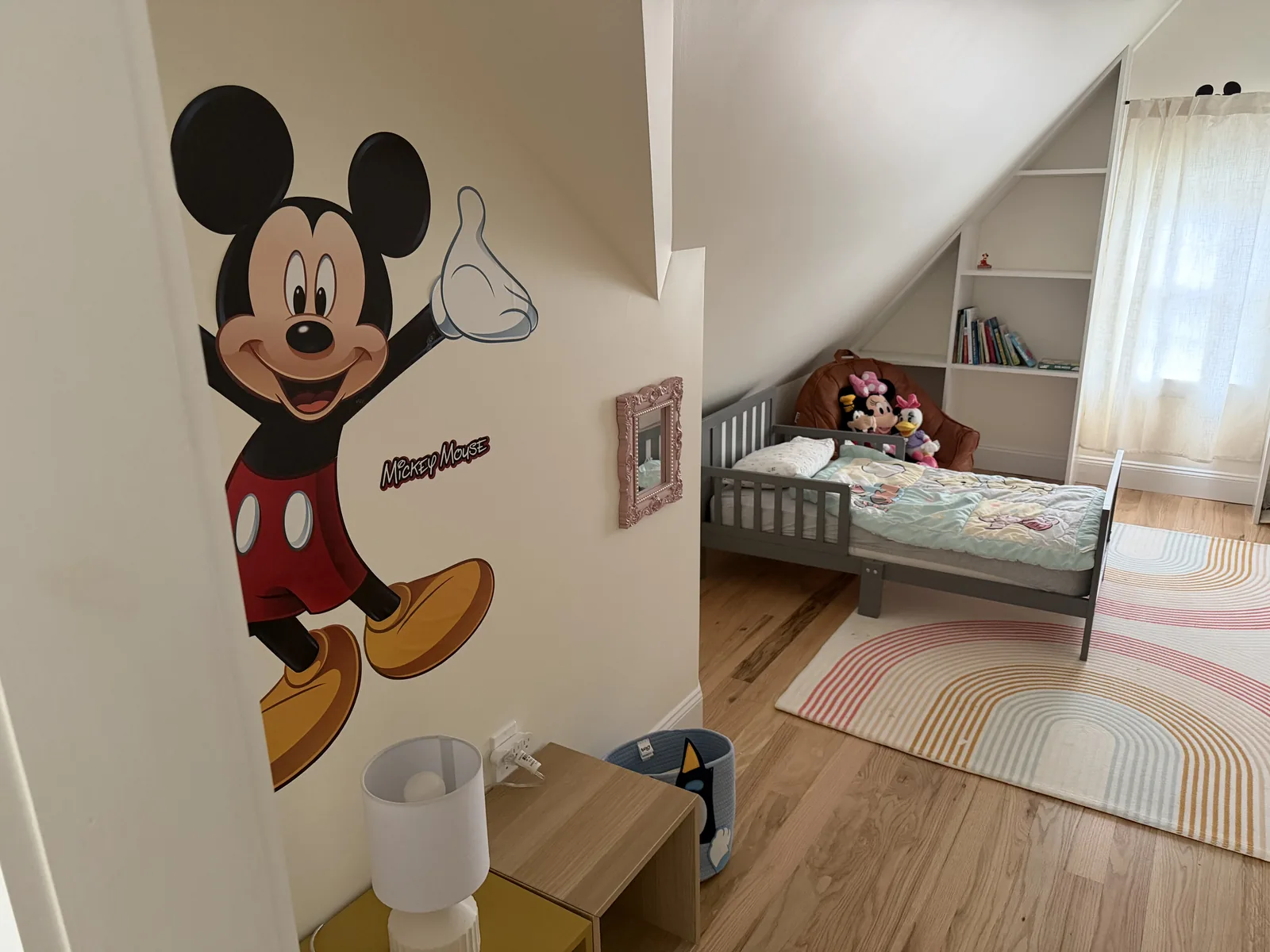 Children's room with a large Mickey Mouse mural and a toddler bed under the eaves